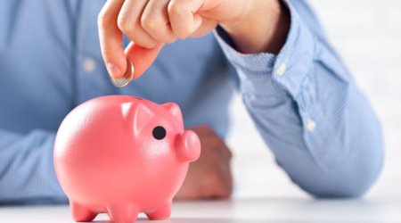 Putting coin into the piggy bank